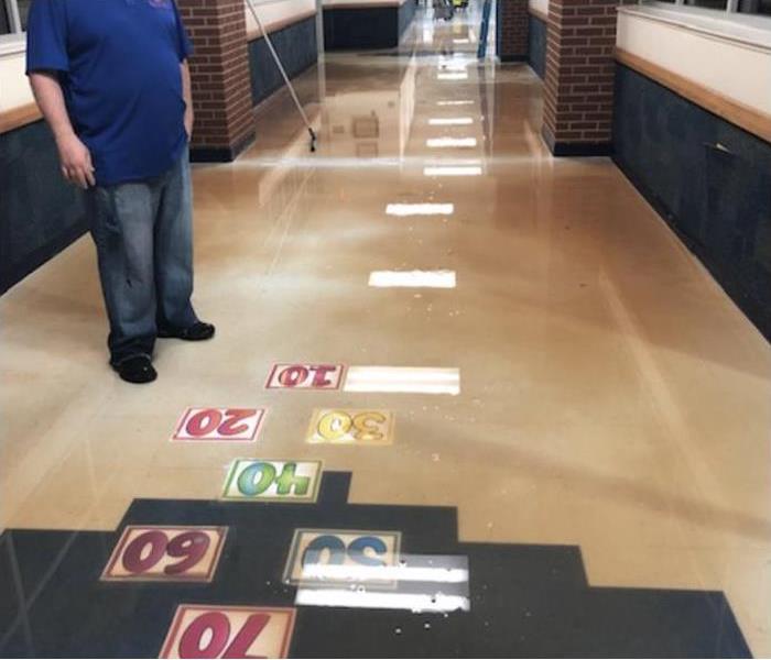 person standing on dirty water in a hallway of a school