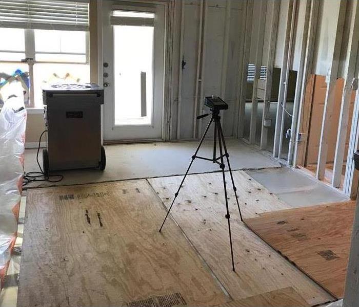 Drywall and carpet removed, dehumidifier and a camera set in the middle of the room